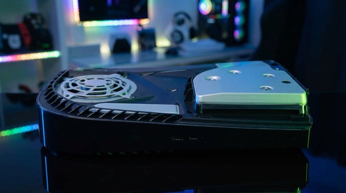 Console aberto com a tampa lateral removida, mostrando a área do slot de expansão